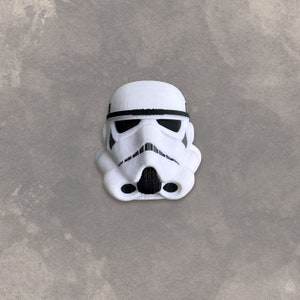 May include: A white plastic Star Wars Stormtrooper helmet with a black visor and black details.