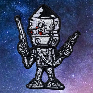 May include: A gray and white embroidered patch of a Star Wars character with a large head and two blasters. The character has a round head with a dome-shaped top and a small body.