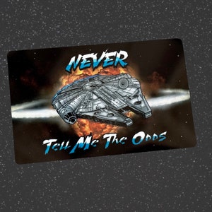 Peut inclure: Une image en noir et blanc d'un vaisseau spatial avec le texte "NEVER TELL ME THE ODDS" en blanc. Le vaisseau spatial est entouré d'une explosion blanche et orange.