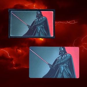 Puede incluir: Un parche bordado con Darth Vader de Star Wars sosteniendo un sable de luz rojo. El parche es negro y rojo y está sobre un fondo rojo oscuro con rayos.