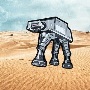 May include: A gray and white AT-AT walker, a fictional vehicle from the Star Wars franchise, is depicted in a desert landscape. The walker is a large, four-legged vehicle with a large, rectangular body and a long neck.