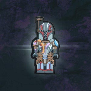 May include: A colorful patch featuring a stylized Mandalorian warrior in a block figure design. The patch has a black border and features a helmet with red, gray, and silver accents, along with armor in shades of brown, orange, and blue. The patch is set against a dark background.
