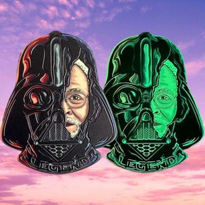 May include: Two black and green enamel pins featuring a Darth Vader helmet with a man's face inside. The text "LEGEND" is printed on the bottom of each pin.