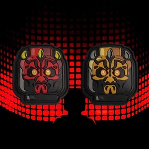 Pode incluir: Dois patches de personagens de Star Wars pretos e vermelhos. Os patches são de Darth Maul e o General Grievous. Os patches estão sobre um fundo vermelho e preto.