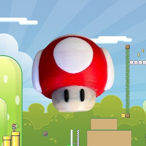 May include: A red and white mushroom-shaped 3D printed object, reminiscent of a Super Mario Bros. power-up. The mushroom is floating in front of a green and blue video game background.
