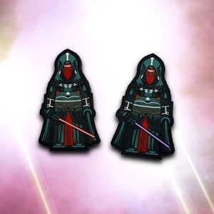 Może przedstawiać: Dwa haftowane naszywki przedstawiające postać ciemnozielonego i czerwonego Lorda Sithów z czerwonym mieczem świetlnym. Postać nosi ciemnozielony płaszcz z kapturem i czerwoną maskę.