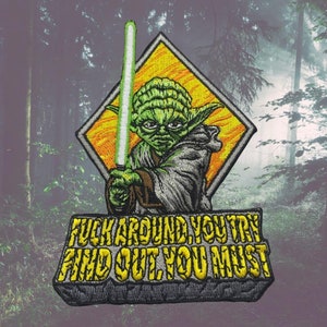 Pode incluir: Um remendo bordado verde e amarelo com Yoda de Star Wars segurando um sabre de luz. O texto "F**k around you try find out you must" está escrito abaixo de Yoda.