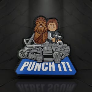 May include: A patch featuring Chewbacca and Han Solo, with the Millennium Falcon, and the text "PUNCH IT!" in white on a blue background. The patch is a detailed, colorful design.