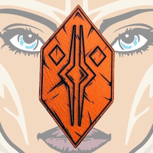 Op de afbeelding: Oranje en zwarte geometrische symboolpatch met een diamantvorm en een textuur.