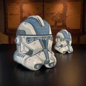 May include: Two white and blue Star Wars Clone Trooper helmet cushions. The helmets are detailed with black markings and a blue stripe.