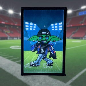 May include: A green cartoon character wearing a blue jacket, black pants, and a black baseball cap with a microphone in hand. The character is standing on a green football field with white yard lines. The background is a blue sky with white lights.