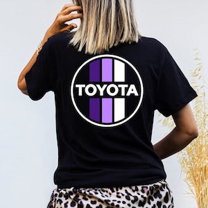 May include: Black t-shirt with a white circle logo featuring the word "TOYOTA" in white letters and purple and white vertical stripes.