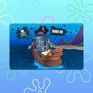 May include: A blue and white robot wearing a pirate hat and holding a treasure chest is sailing on a wooden boat with a black pirate flag. The text "ARR2-D2" is on the flag.