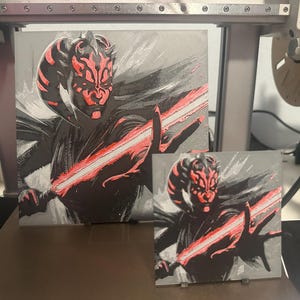 May include: Two black and red illustrations of Darth Maul, a Star Wars character, wielding a red lightsaber. The larger illustration is on a white background, while the smaller illustration is on a grey background.