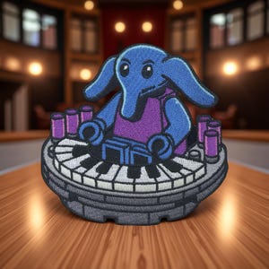 May include: Embroidered patch featuring a blue elephant playing a piano. The elephant wears a purple shirt and sits on a keyboard-shaped base. Purple cylinders are placed around the keyboard. The patch has a detailed, cartoon-like design.