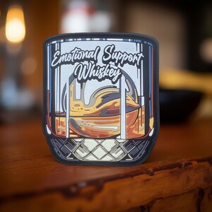 May include: A black and white illustration of a glass of whiskey with the text "Emotional Support Whiskey" on the side.