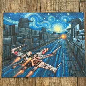 May include: A rectangular art print featuring a white and red starfighter flying through a trench between two gray metallic structures. The background displays a swirling blue night sky with a bright yellow moon and glowing orange engine exhaust.