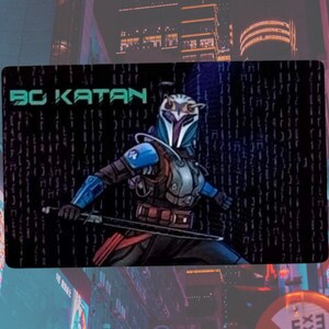 May include: A black and green digital art print featuring a character from the Star Wars universe. The character is wearing a blue and red outfit and a helmet with a white visor. The text "BG KATAN" is displayed in green letters at the top of the print.