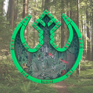 May include: A green and red emblem featuring a Star Wars-themed design. The emblem is set against a forest backdrop and includes illustrations of AT-ST walkers and other characters. The emblem is approximately 30 cm in diameter.