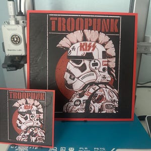 May include: Two framed prints with a red border and a black background. The prints feature a stylised illustration of a Stormtrooper helmet with a mohawk and the text "TROOPUNK" in red letters. The helmet has the word "KISS" written on it.