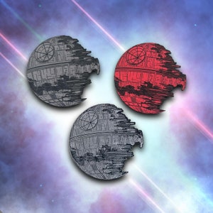 May include: Three Death Star-shaped pins in gray and red, with detailed surface designs. The pins are set against a space-themed background with streaks of light, showcasing a sci-fi theme.