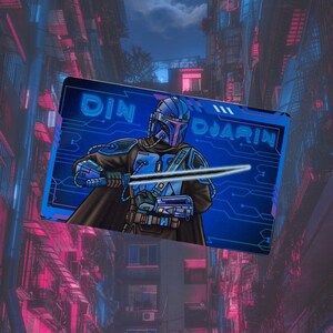 May include: A blue and white illustration of a Mandalorian character with a lightsaber, against a blue background with a circuit board pattern. The text "DIN DJARIN" is in white letters on the top right corner of the image.