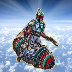 May include: An embroidered patch featuring Boba Fett from Star Wars riding his jetpack. The patch is green, red, and brown with a yellow outline.