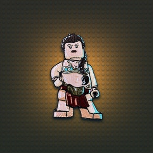 May include: A brown-haired Lego minifigure of Princess Leia with a white and blue bikini top, a brown belt, and a red skirt. The minifigure is standing on a brown background.