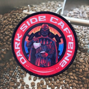 May include: A red and black circular patch with the text "Dark Side Caffeine" in white. The patch features a cartoon image of Darth Vader pouring coffee from a pitcher into a cup.