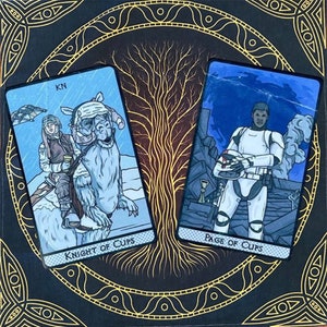 May include: Two Star Wars themed tarot cards. The Knight of Cups card features a character riding a white creature in a snowy landscape. The Page of Cups card features a character in a white and black suit holding a helmet. Both cards have a blue background and are framed in gold.