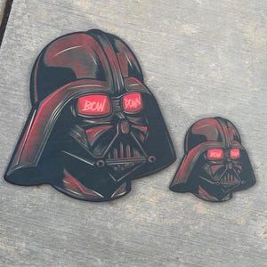 Op de afbeelding: Twee zwarte en rode Darth Vader stickers met de tekst "BOW DOWN" op de ogen.