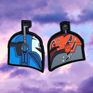 May include: Two Star Wars clone trooper helmet patches. The left patch is blue, white, and black. The right patch is orange, gray, and black.
