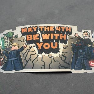 Może przedstawiać: Naklejka przedstawiająca postacie z Gwiezdnych Wojen w stylu Lego. Postacie to Darth Vader, Yoda, Obi-Wan Kenobi i inni. Tekst na naklejce brzmi "May the 4th Be With You".