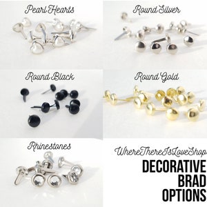 May include: Assortment of decorative metal brads in various shapes and colors, including pearl hearts, round silver, round black, round gold, and rhinestones.  Where There Is Love Shop DECORATIVE BRAD OPTIONS.