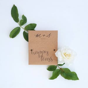 May include: A brown card with the text "M & S 09.03.17" and "For a happy tears" with a white rose and green leaves.