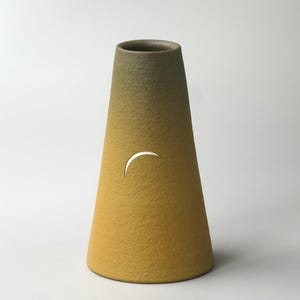 Pode incluir: Um vaso cónico de cerâmica com uma superfície texturizada que transita de um verde azeitona profundo no topo para um amarelo mostarda vibrante na base. O vaso apresenta um pequeno recorte em forma de meia-lua na frente, revelando o interior.