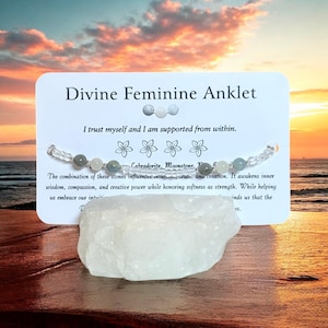 Può includere: Una cavigliera Divine Feminine con perline di labradorite e pietra di luna. La cavigliera è esposta su una carta bianca con testo e un cristallo bianco. La carta recita "Mi fido di me stesso e sono supportato dall'interno."