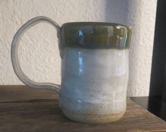 Rustic mug made from Missouri Gold clay. Copper blue & Eggshell glaze. Textured handle. Holds 8 ounces.