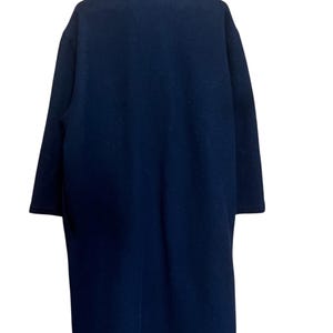May include: A navy blue overcoat with a high collar. The coat is long, reaching below the knees, and has long sleeves. The fabric appears to be a soft, woven material.
