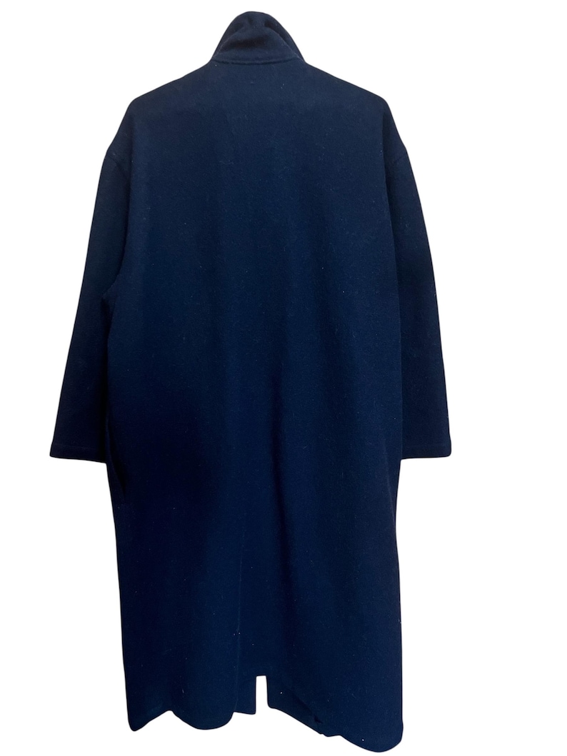 May include: A navy blue overcoat with a high collar. The coat is long, reaching below the knees, and has long sleeves. The fabric appears to be a soft, woven material.
