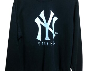 May include: Black crewneck sweatshirt featuring the New York Yankees logo in white. The logo includes the letters "NY" in a stylized design, with the word "Yankees" printed below. The sweatshirt is hanging on a black hanger.