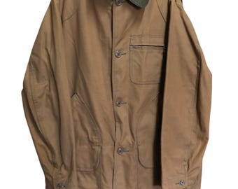 May include: A brown jacket with a corduroy collar and multiple pockets. The jacket has a button-up front and is hanging on a black hanger. The jacket appears to be made of a durable, possibly water-resistant material.
