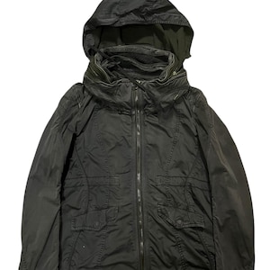 May include: Dark olive green hooded jacket with a full-length zipper closure. The jacket features two front pockets, a high collar, and a drawstring hood. The jacket is made of a lightweight material.
