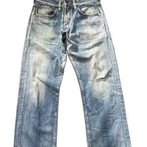 May include: Faded blue denim jeans with a distressed look. The jeans have a button fly, classic five-pocket design, and a worn patch on the right knee. The denim has a light wash with fading and whiskering details.
