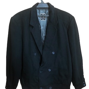 May include: A black double-breasted jacket with a notched lapel and a bomber-style hem. The jacket features four front buttons and two on each cuff. The lining is visible and has a label that reads "Zilii".