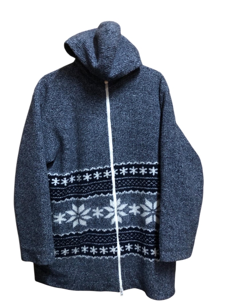 May include: A gray hooded zip-up sweater with a white zipper. The sweater features a snowflake pattern in white and navy blue across the chest. The knitwear has a textured appearance and a high collar.