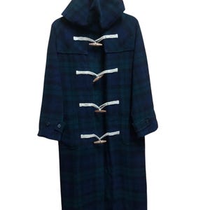 May include: A long, navy blue and green plaid duffel coat with a hood. The coat features wooden toggles and white rope closures. The coat has two front pockets and buttoned cuffs. The coat is made of a thick, warm material.