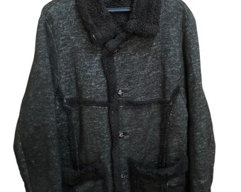 May include: A dark gray jacket with a black faux fur collar and trim. The jacket has a button-up front, two front pockets, and a textured appearance. The jacket is hanging on a black hanger.