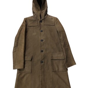 May include: A brown hooded coat with a button-up front and two front pockets. The coat has a long length and a simple, classic design. The hood is attached and the coat appears to be made of a durable material.