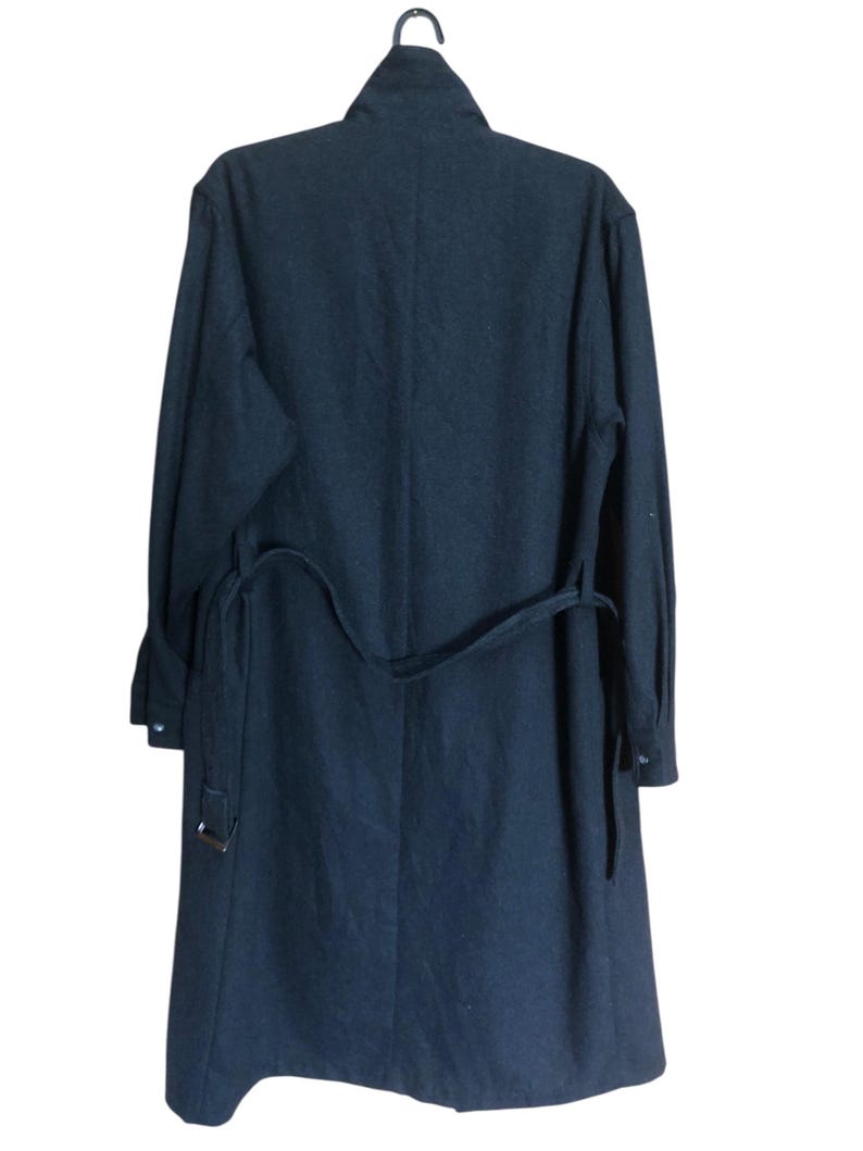 May include: A dark navy blue coat with a matching belt. The coat is hanging on a black hanger. The coat has long sleeves and a collar.